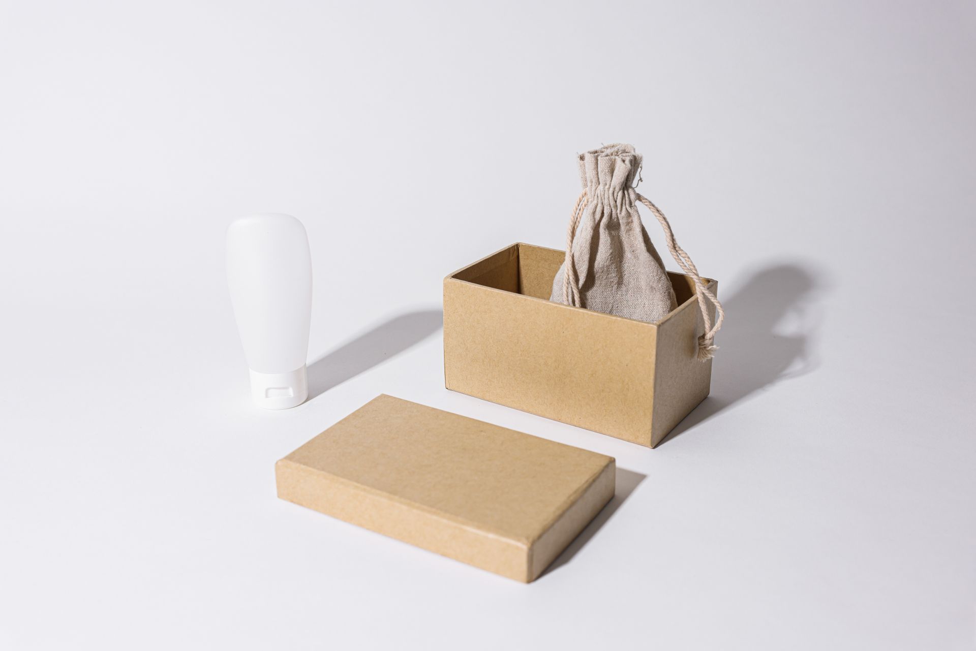 Minimalist product packaging mockup with a cardboard box, linen pouch and tube